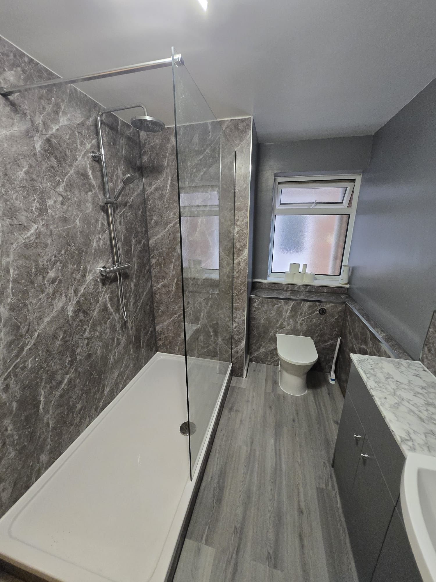 Grey bathroom with walk-in shower and marble effect panels