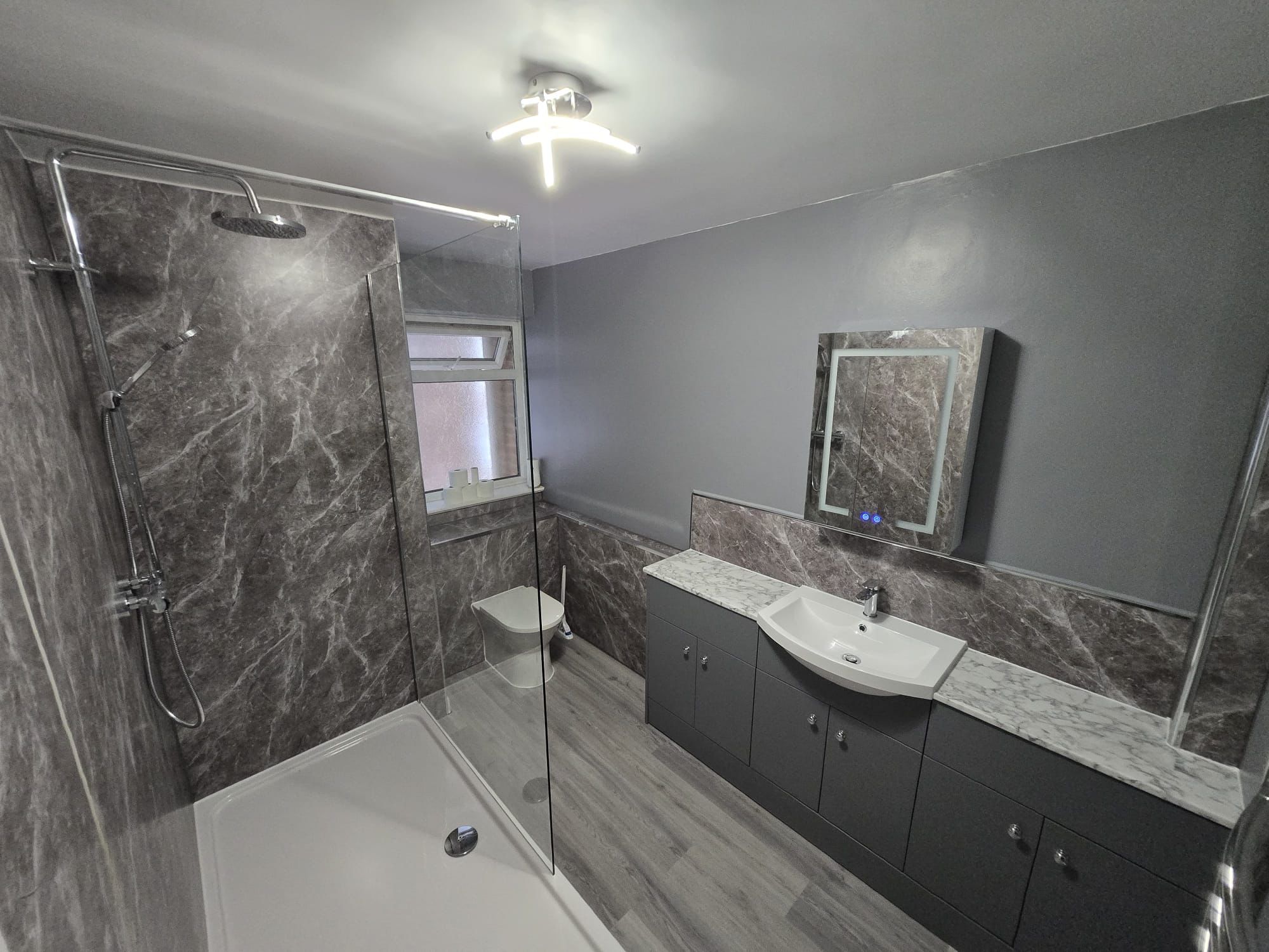 Modern grey bathroom with walk-in shower, vanity unit and mirror cabinet