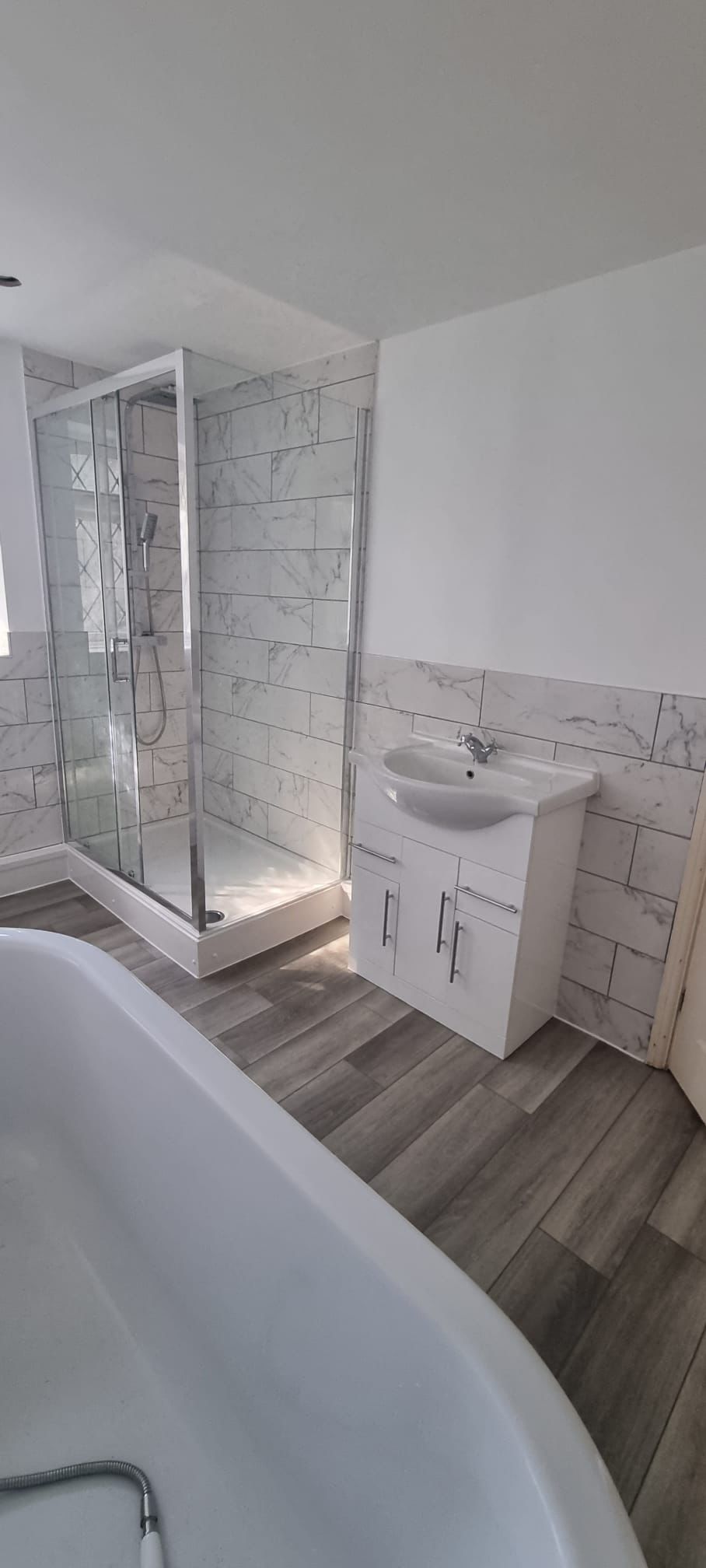 Bathroom renovation with bath, shower enclosure and marble effect wall tiles