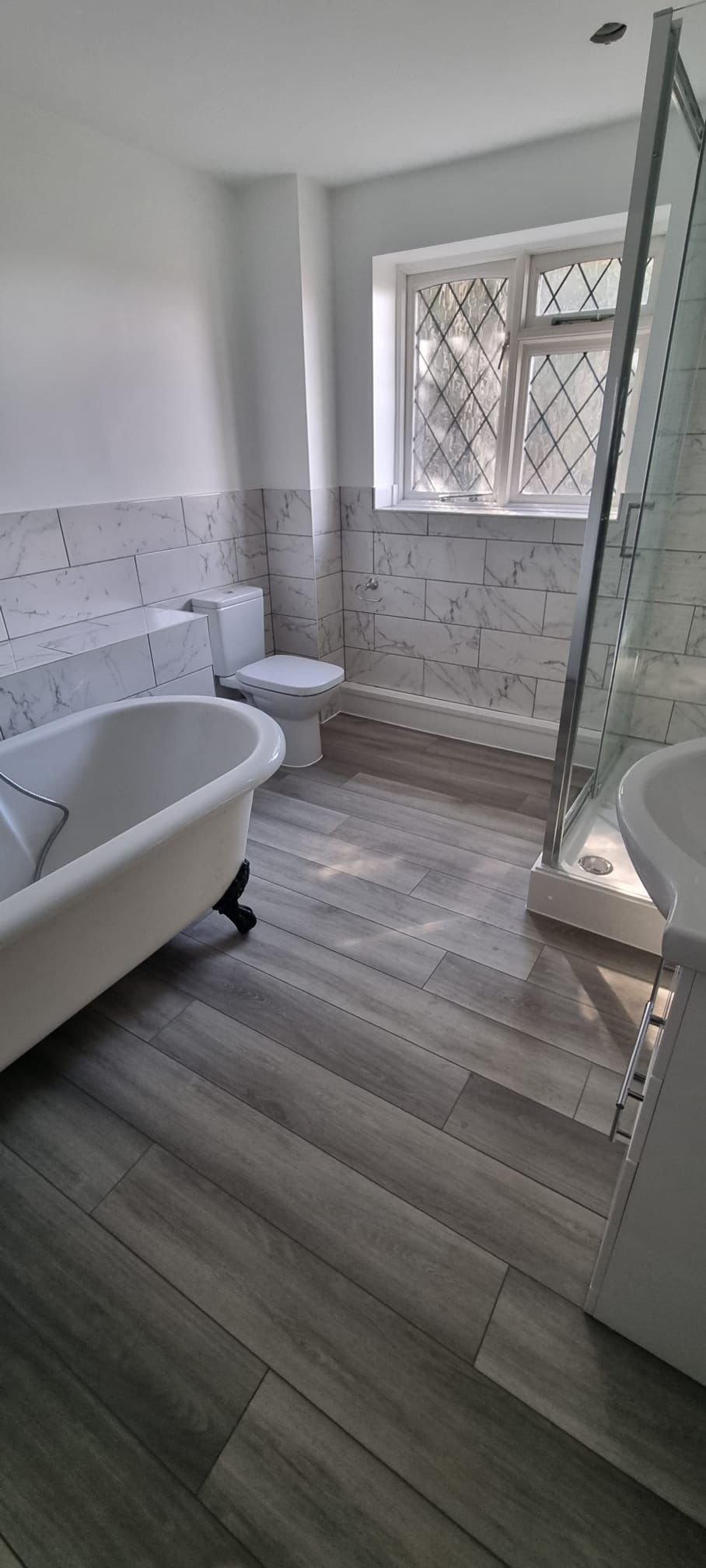 Bathroom with freestanding bath, shower enclosure and marble effect tiling