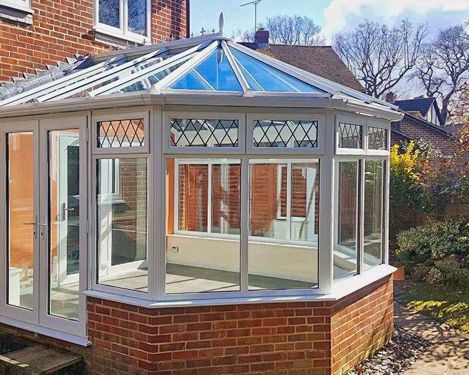 White conservatory extension with brick base and glazed roof