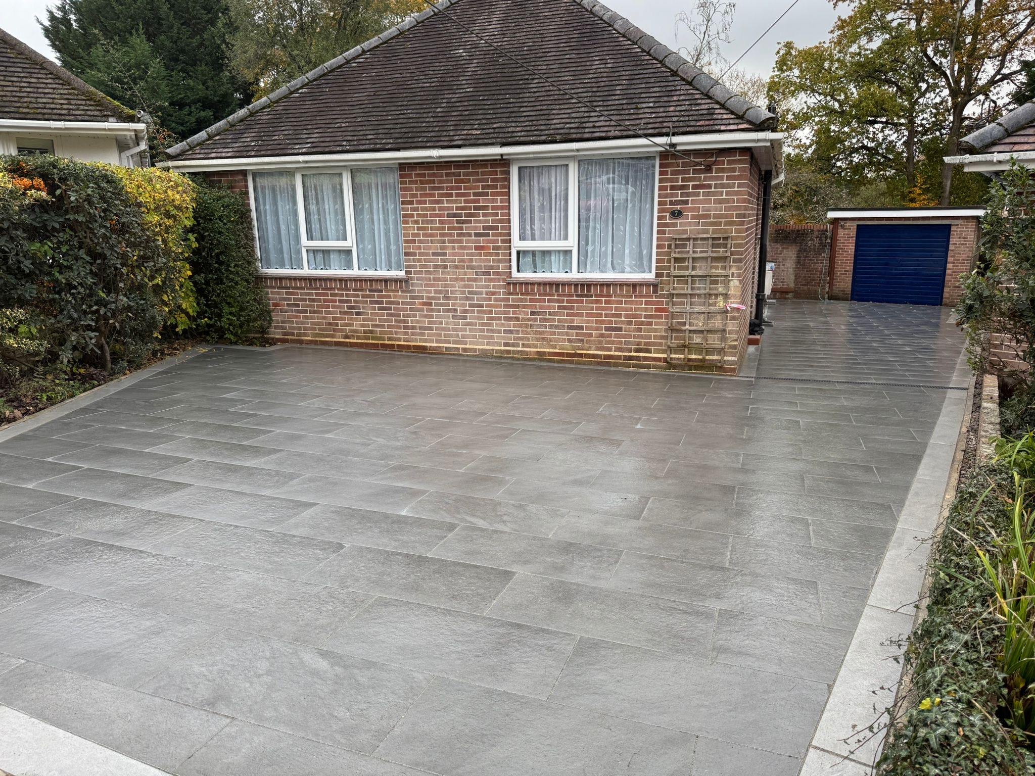 Large grey porcelain driveway outside a brick bungalow