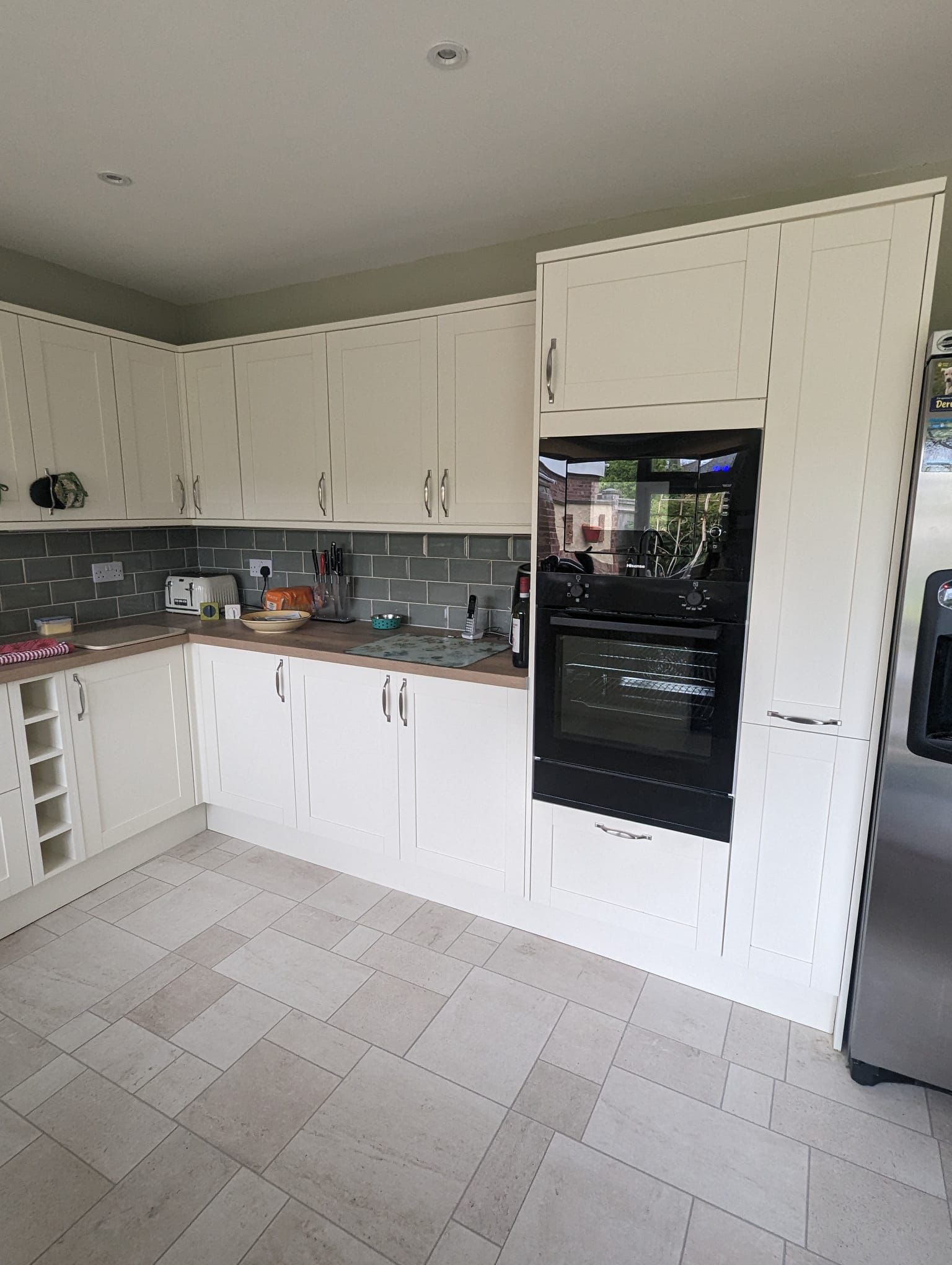 Cream fitted kitchen with grey tile splashback and integrated oven