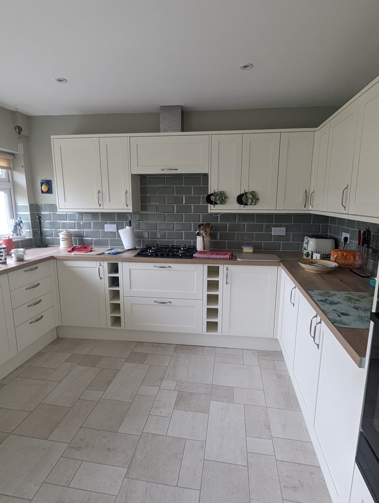 Cream fitted kitchen with grey splashback and wood effect worktops