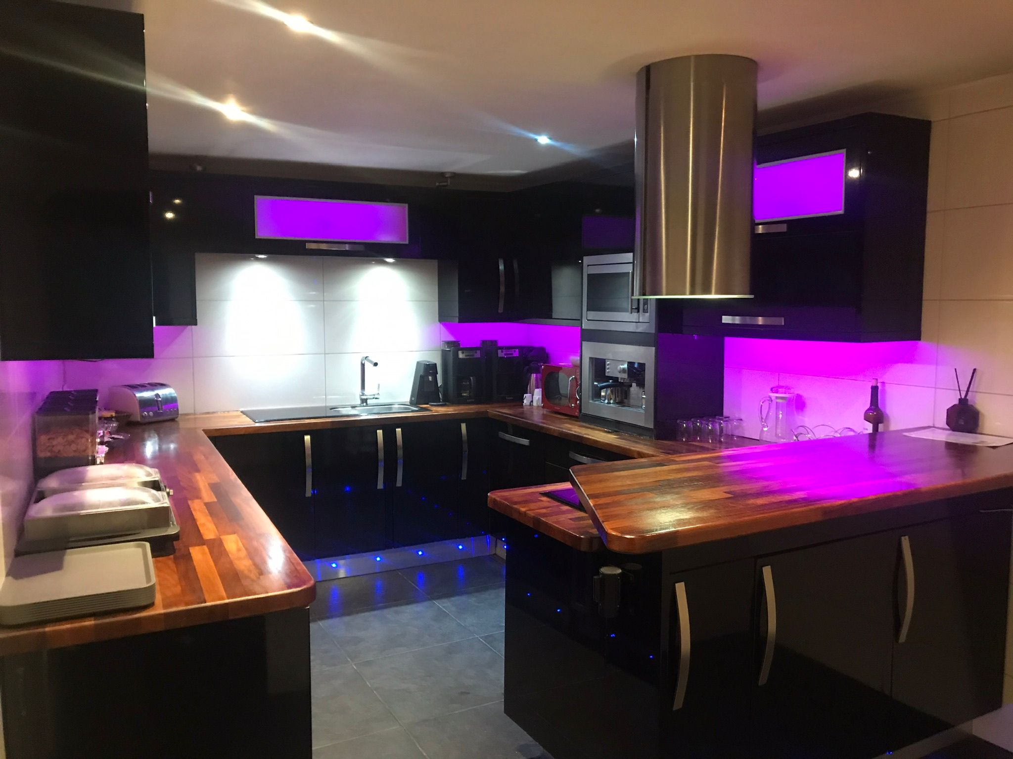 Gloss black kitchen with wood worktops and feature lighting