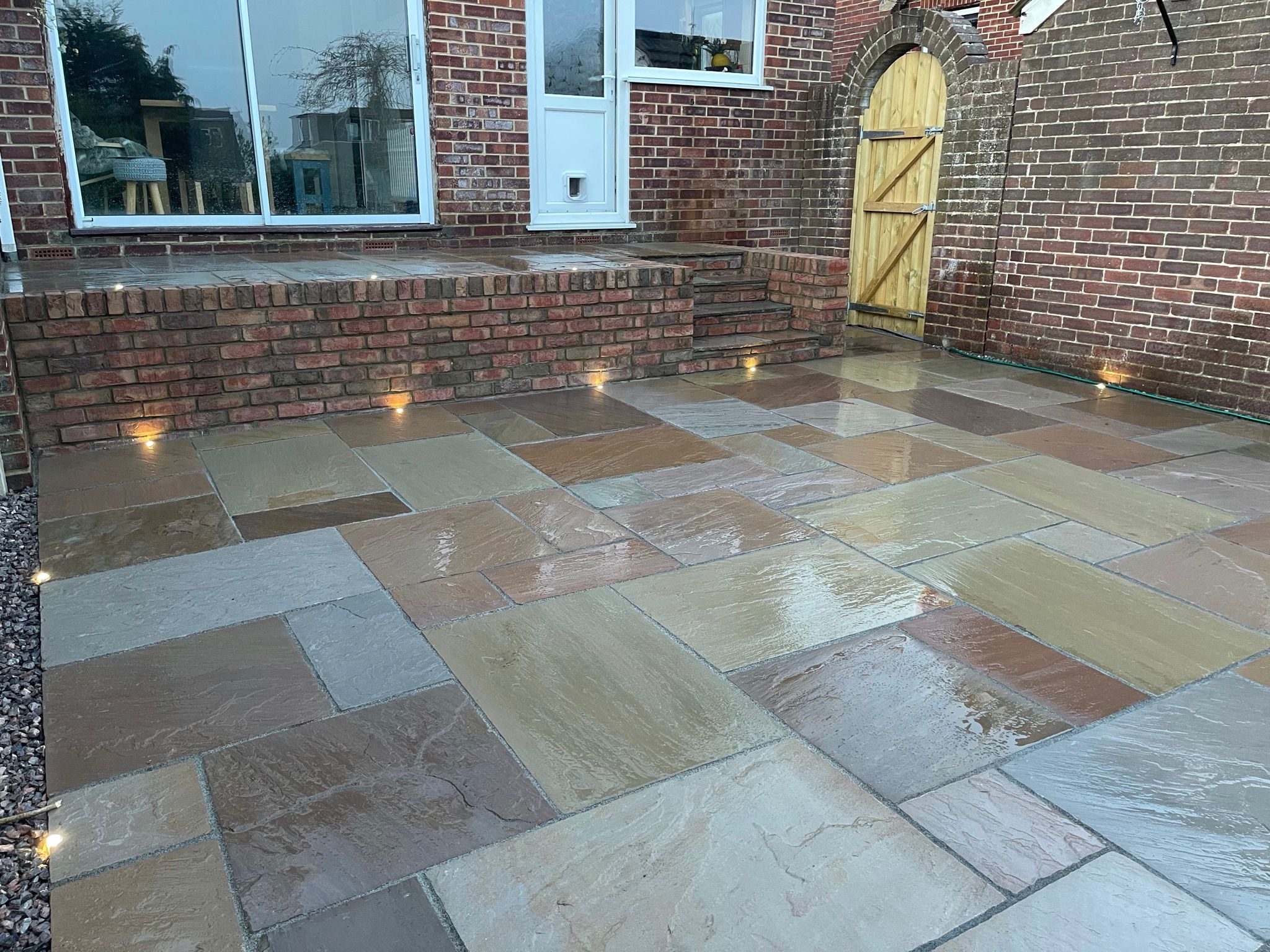Natural stone patio with brick steps and wall lighting