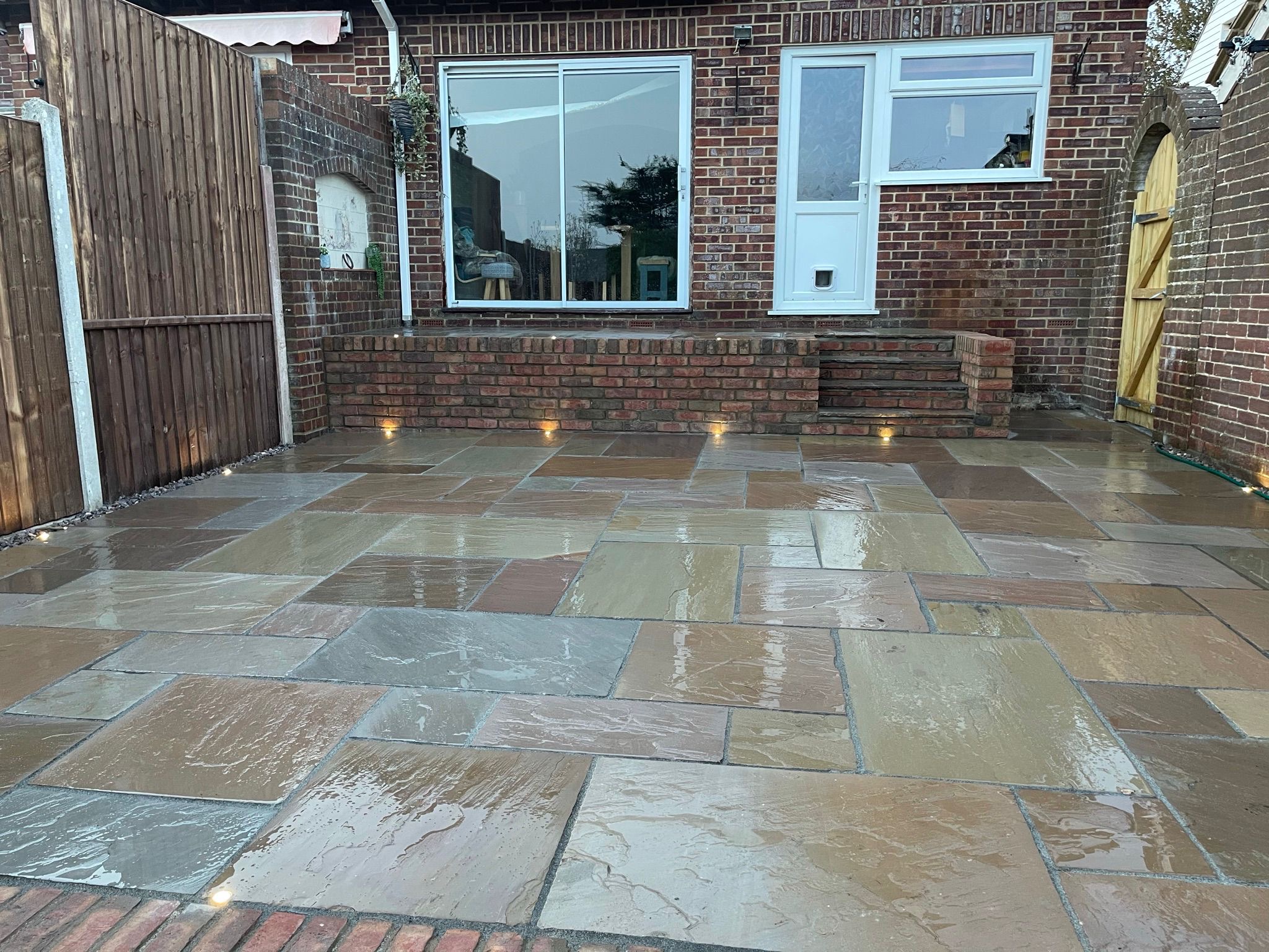 Natural stone patio with brickwork steps and warm lights