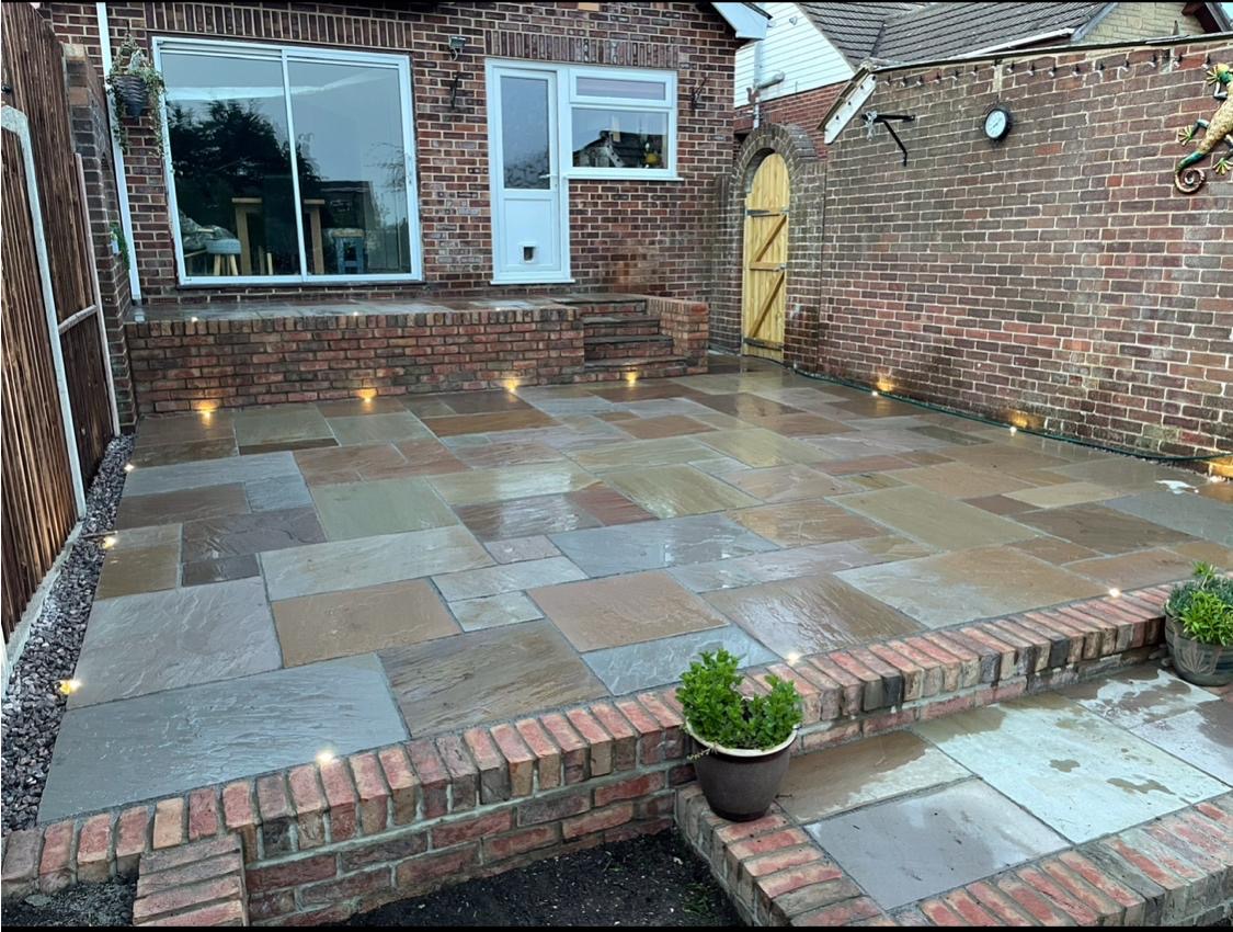 Natural stone patio with brick raised terrace and lighting