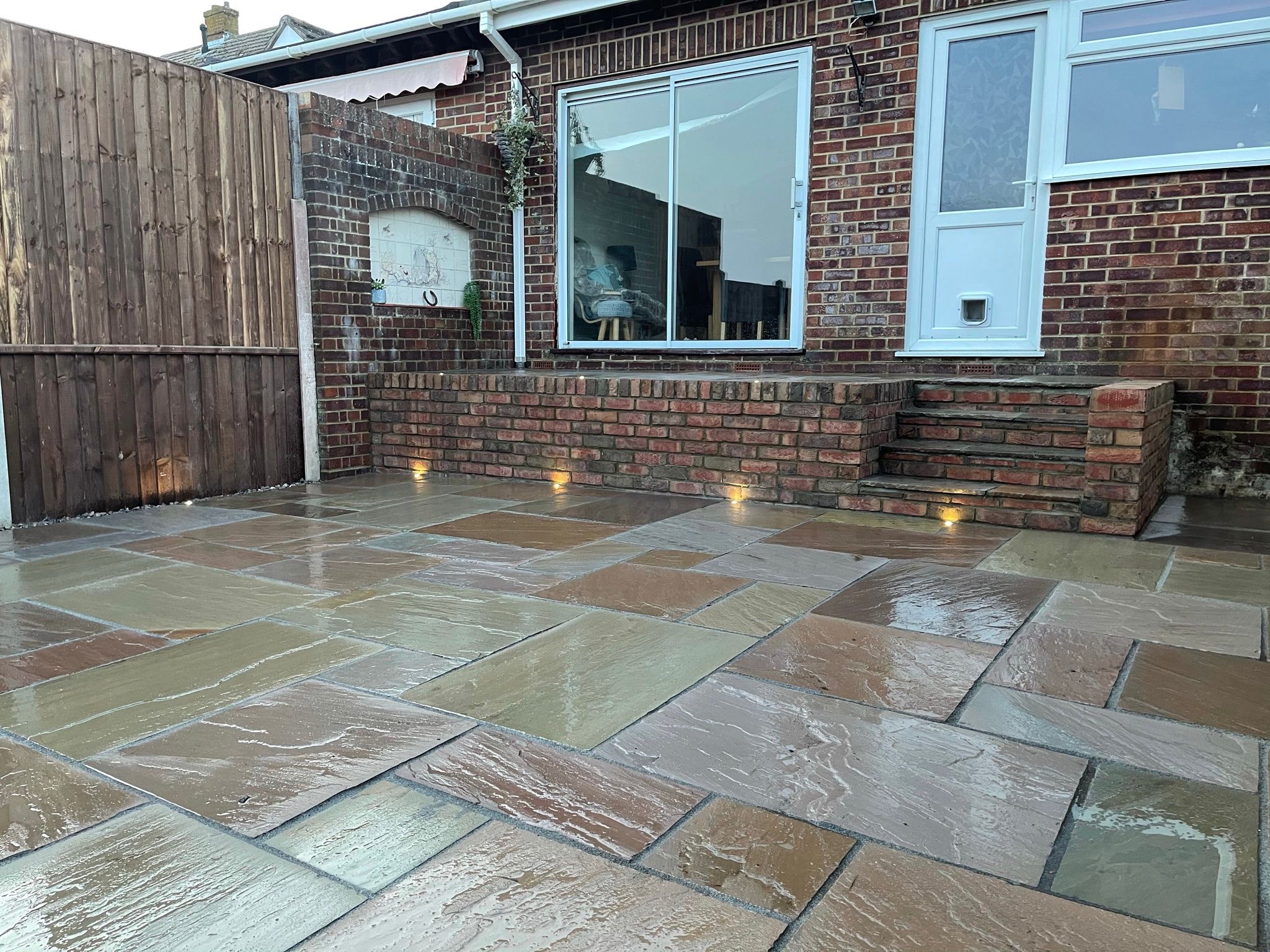 Natural stone patio and brick steps beside a house