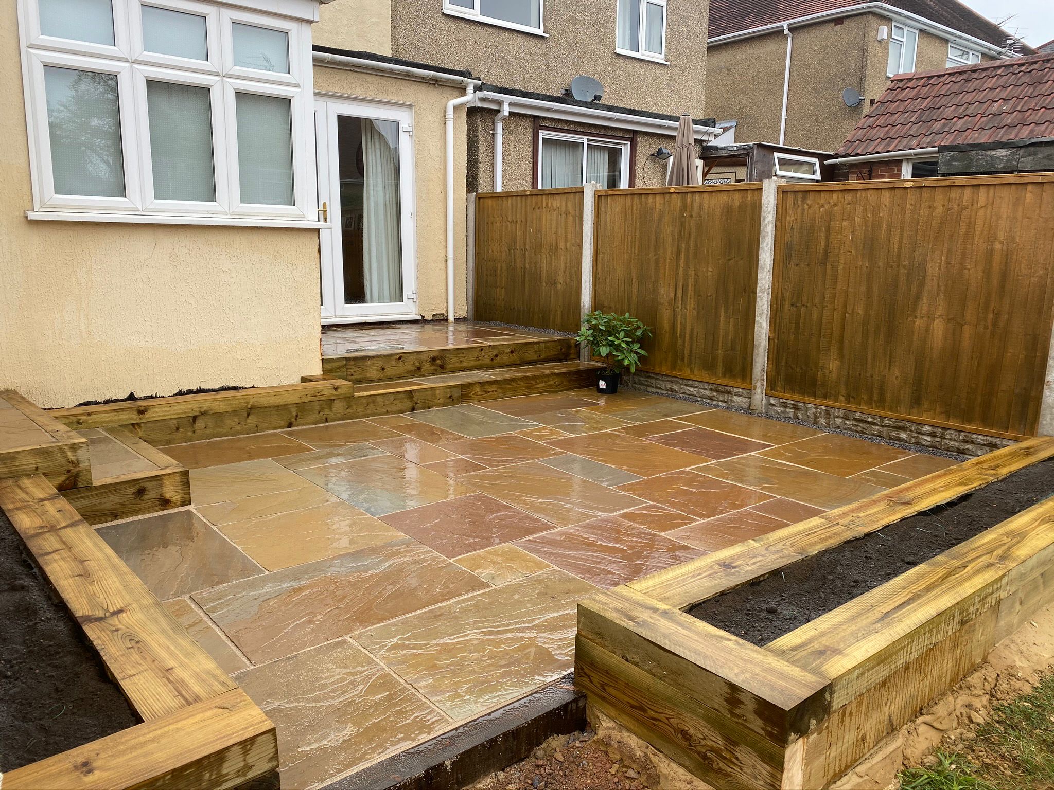 Natural stone patio with timber raised beds and steps
