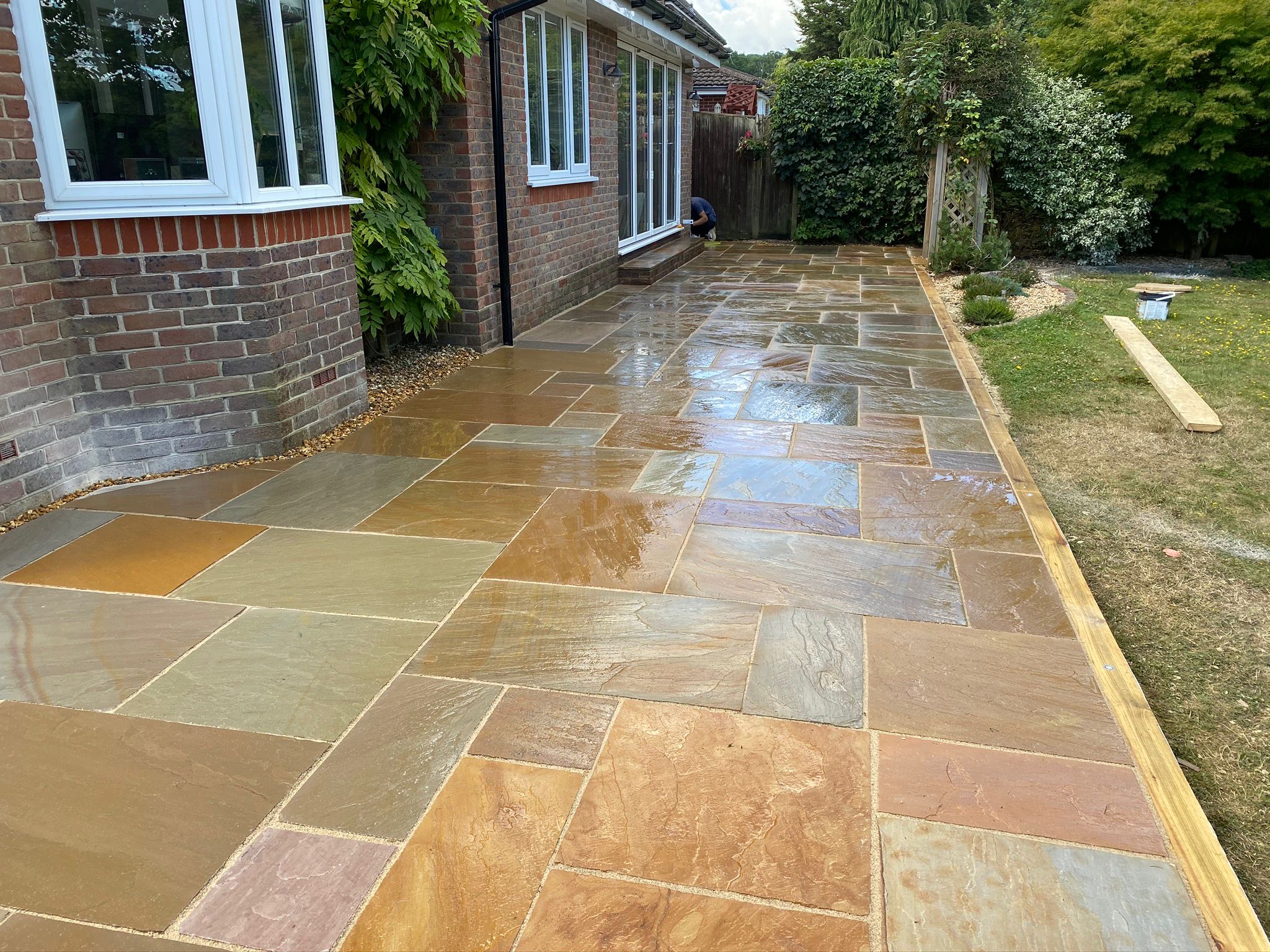 Natural stone patio laid along the side of a house