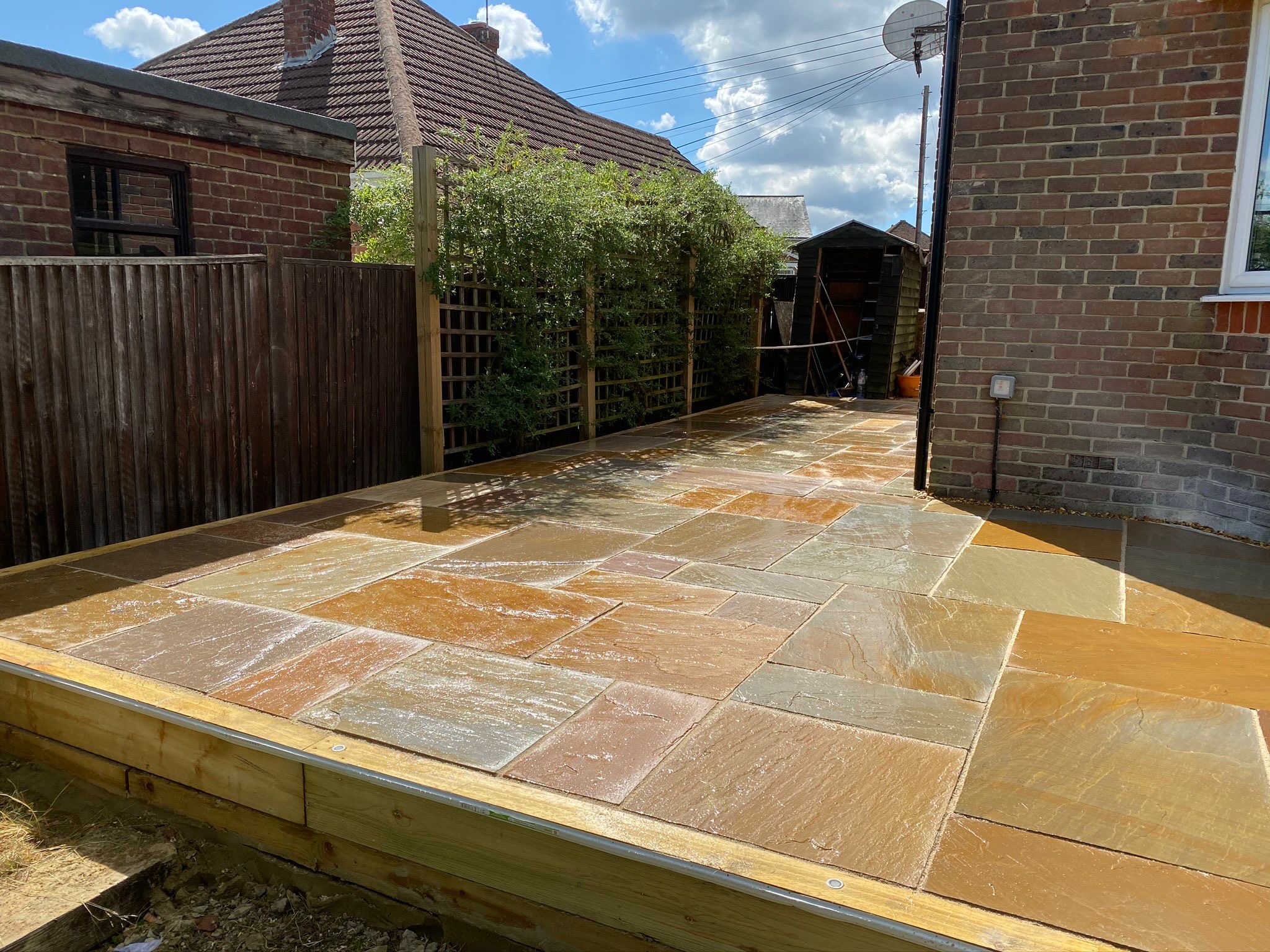 Natural stone side patio with timber edging and fencing