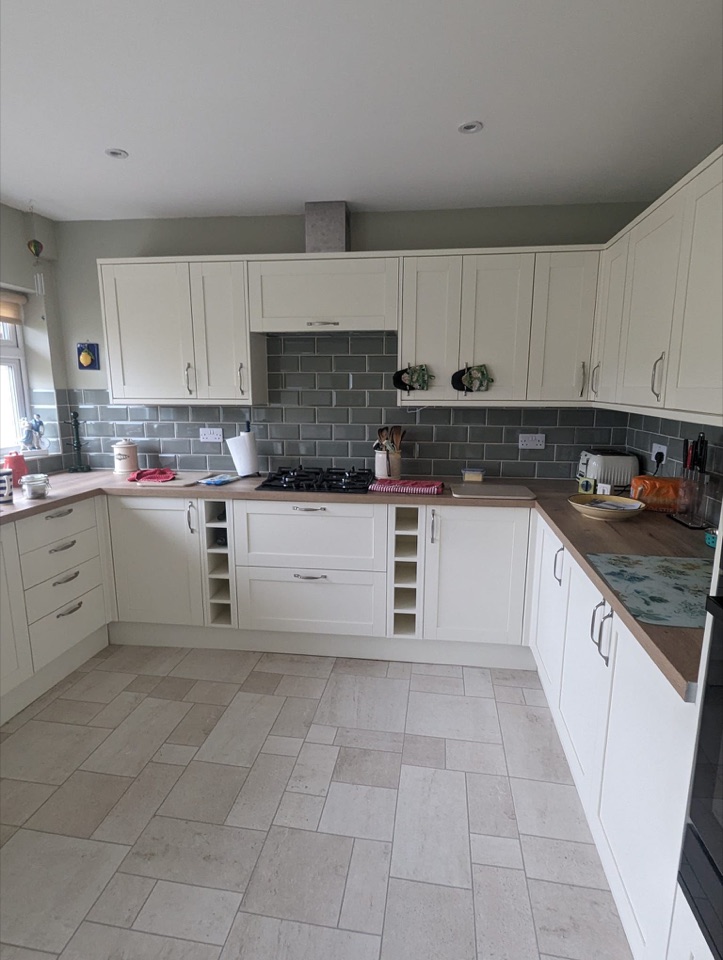 Cream fitted kitchen with grey splashback and wood effect worktops