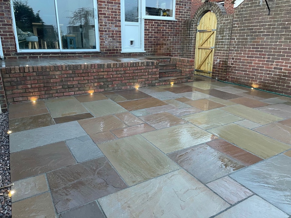 Natural stone patio with brick steps and wall lighting