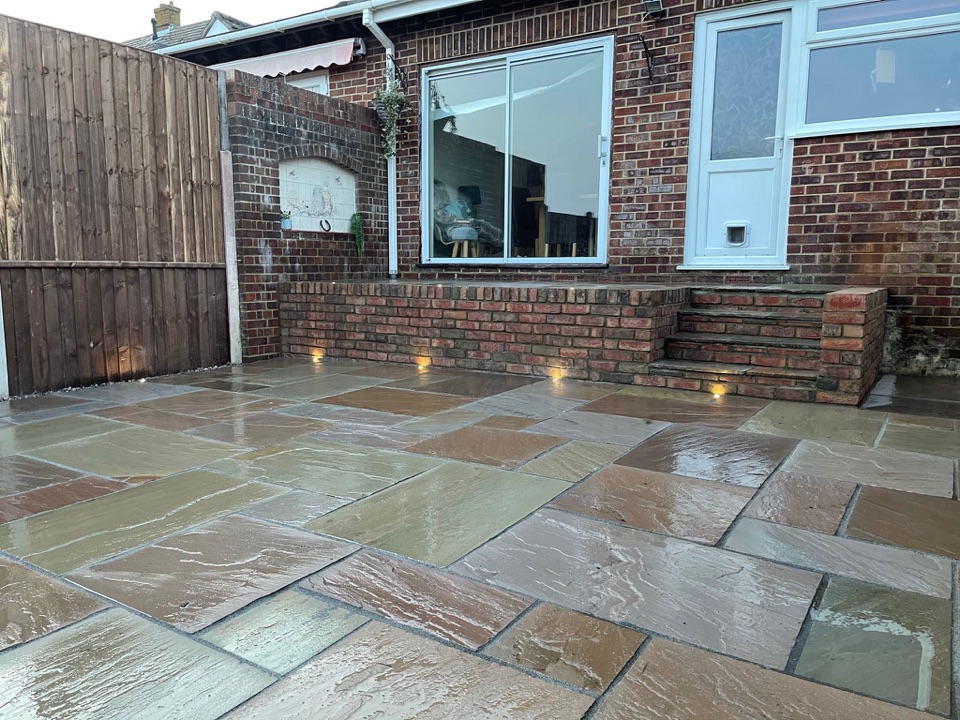 Natural stone patio and brick steps beside a house