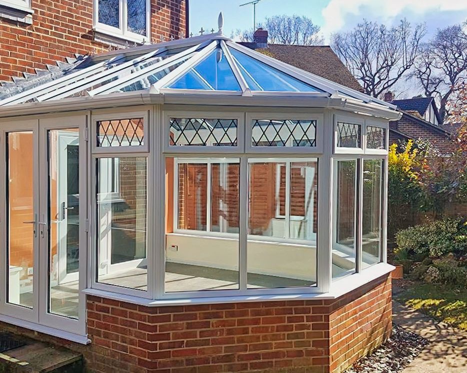 Glazed conservatory exterior with white frames and brick base